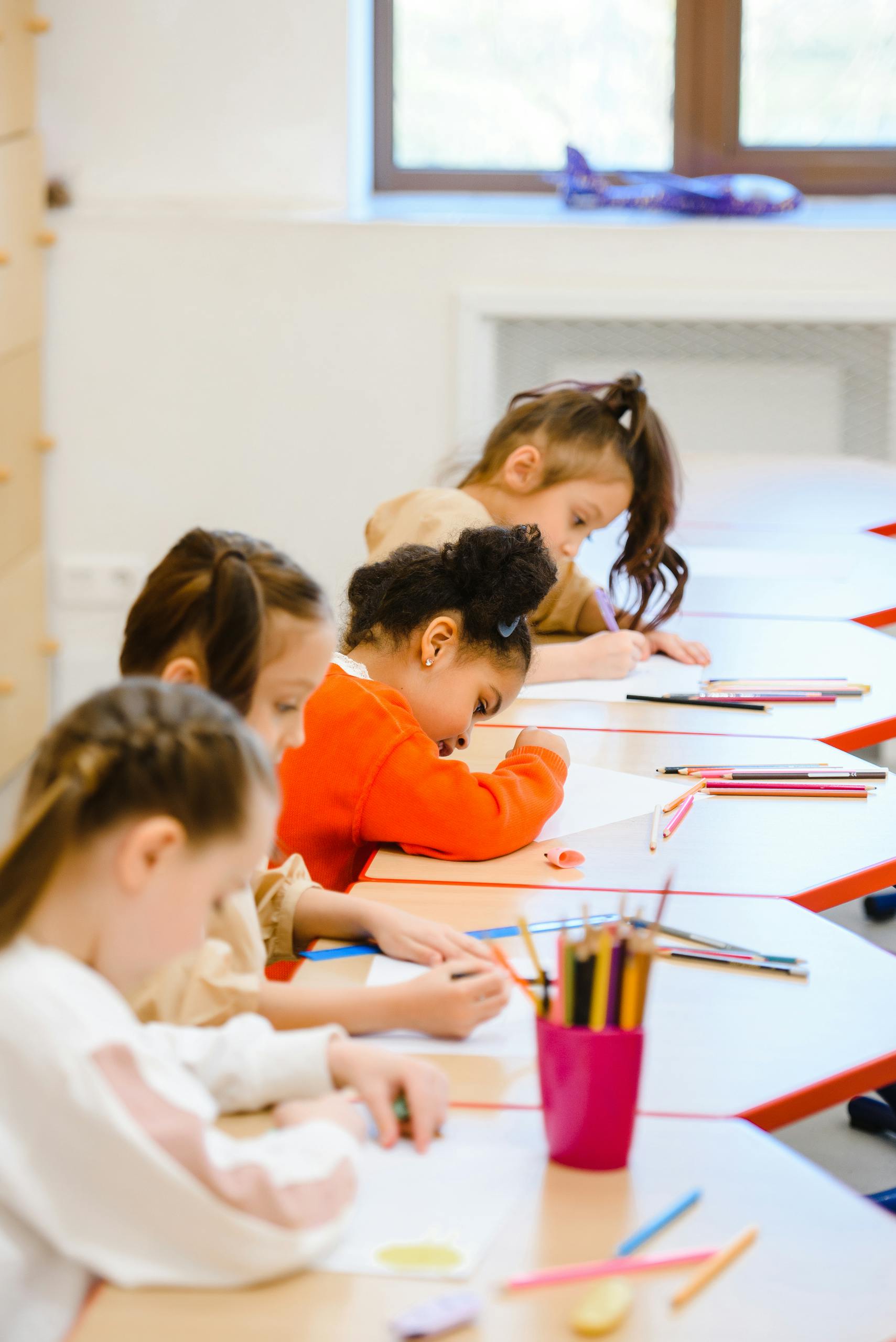 Group of children focused on schoolwork in a bright classroom setting.